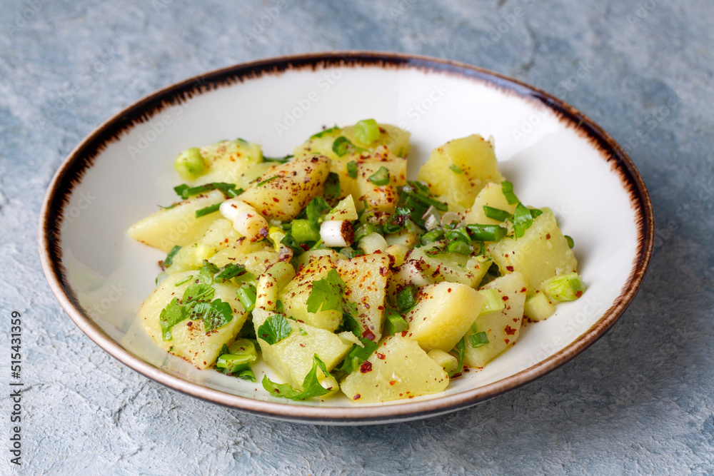 Potato salad with green onion on white plate over wooden background with copy space. Top view. Potato salad with green onion on white plate over wooden background with copy space. Top view.