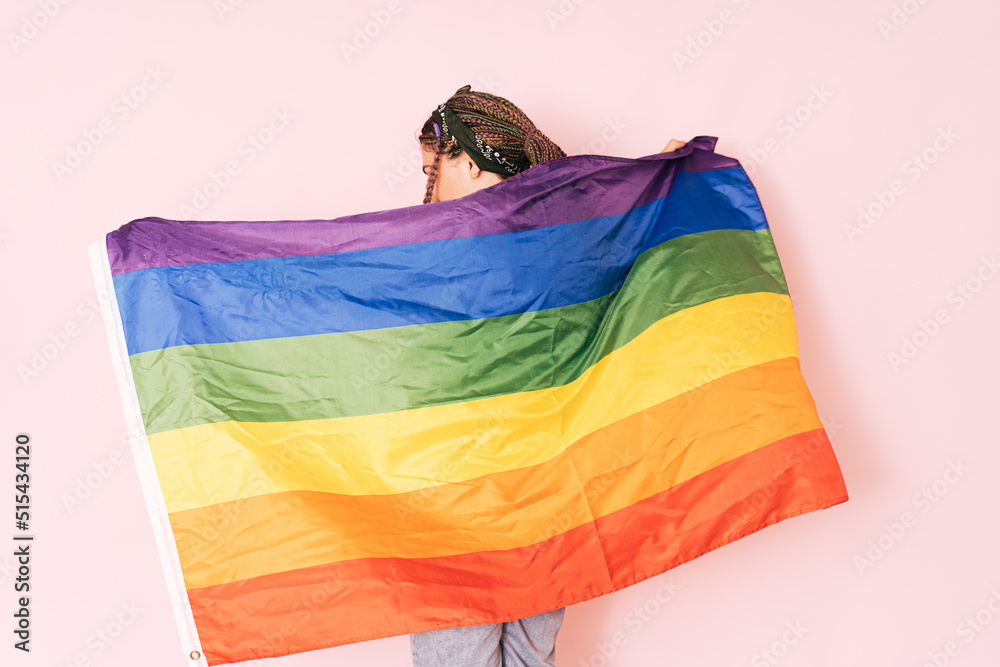 Girl with LGBT flag on her back against a pink background.