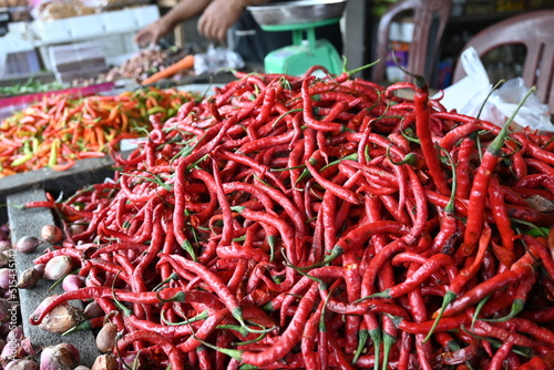 selective focus of long red chilies being sold in a vegetable stall. 