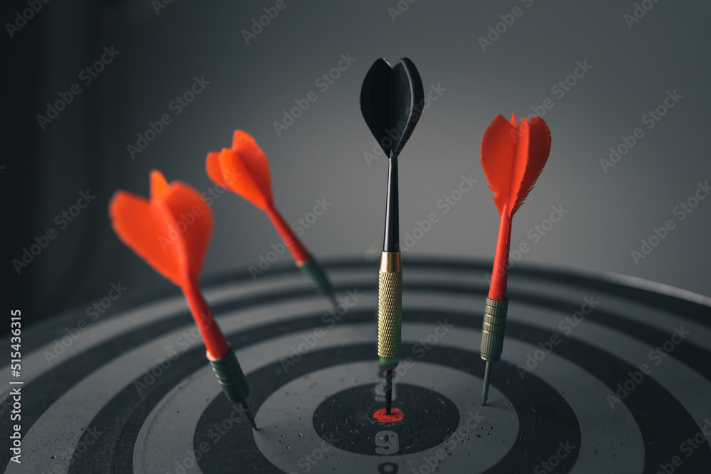Close up shot of the dart arrow hit on bulleyes of dartboard to represent that the business reached the target of company with dark tone picture style. Target and goal as concept. Close up shot of the dart arrow hit on bulleyes of dartboard to represent that the business reached the target of company with dark tone picture style. Target and goal as concept.