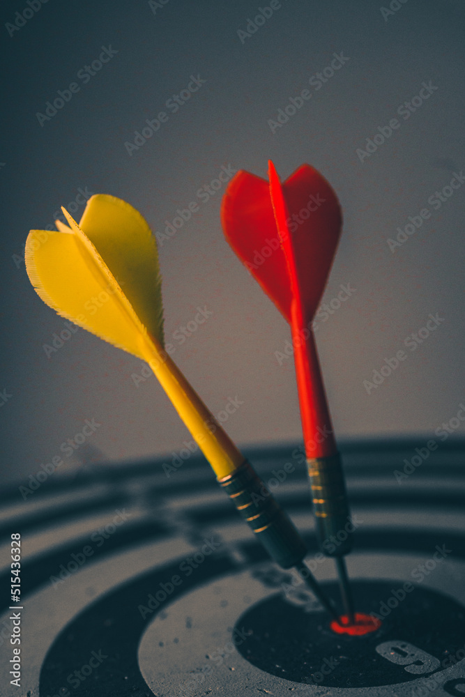 Close up shot of the dart arrow hit on bulleyes of dartboard to represent that the business reached the target of company with dark tone picture style. Target and goal as concept. Close up shot of the dart arrow hit on bulleyes of dartboard to represent that the business reached the target of company with dark tone picture style. Target and goal as concept.