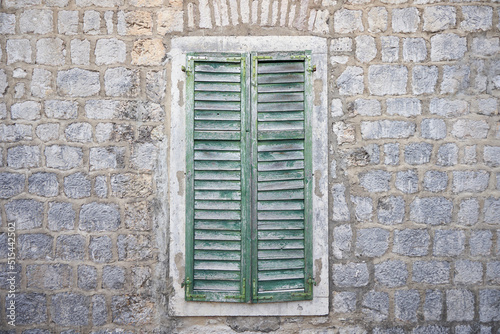 Aged wooden shutters on a window on a stone wall © pridannikov