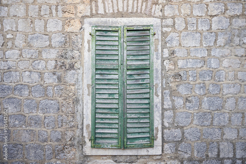 Aged wooden shutters on a window on a stone wall