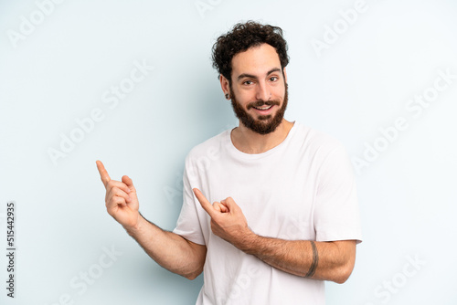 Fotografie, Obraz young adult bearded man smiling happily and pointing to side and upwards with bo