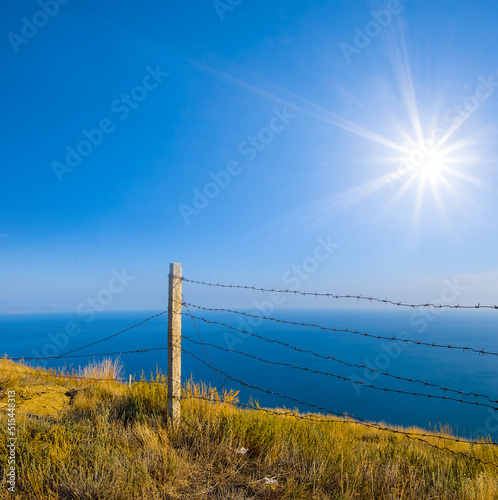 barbed wire fence on sea cliff at sunny day