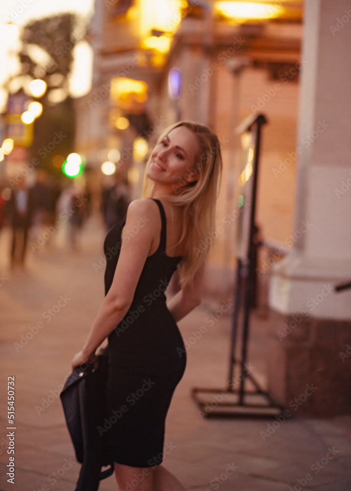 Smiling blond woman posing in fashion style clothes walking on city street summer night lights background. outdoor portrait. Blur unfocus art portrait. vintage Smiling blond woman posing in fashion style clothes walking on city street summer night lights background. outdoor portrait. Blur unfocus art portrait. vintage