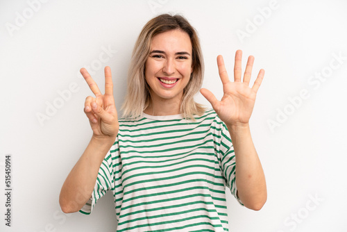 Foto young adult blonde woman smiling and looking friendly, showing number seven or s