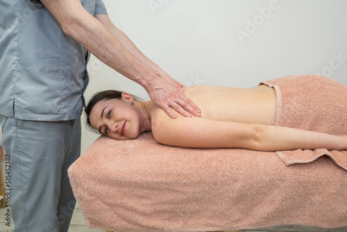 A male massage therapist makes a back and body massage to a young beautiful brunette woman.