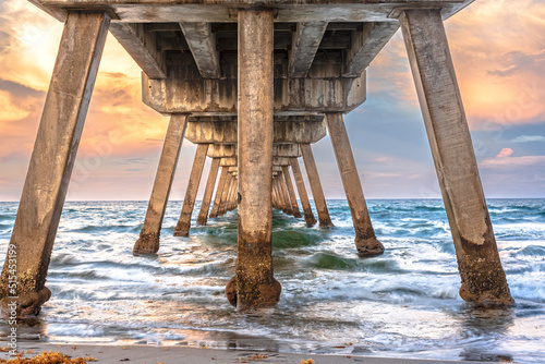 under view of concrete pier over ocean with sunset 