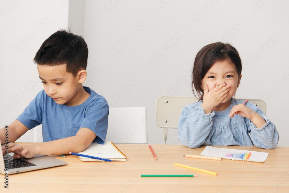 cute children boy and girl sit at a desk in class and play around cute children boy and girl sit at a desk in class and play around