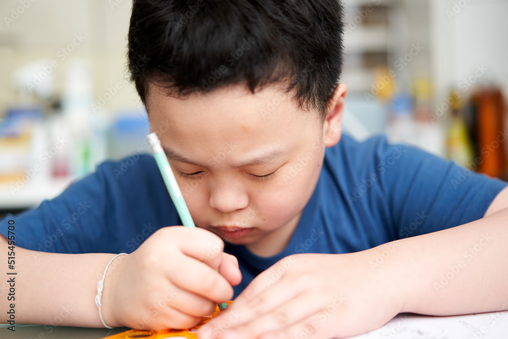 asia boy concentrating to write book asia boy concentrating to write book