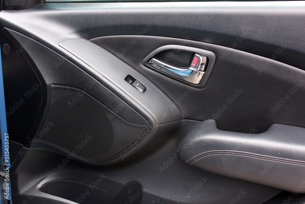 Lux Car interior. Car door trim, door handle and control buttons. Front door panel. Lux car door handle and control buttons.