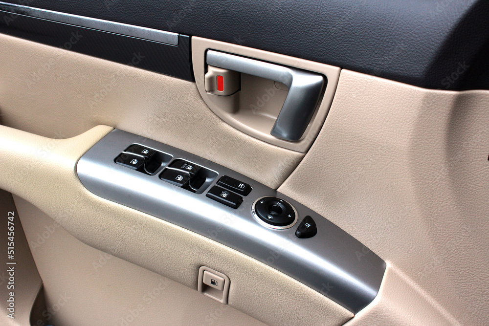 Door handle with windows controls and adjustments in light leather interior. Window switches. Door handle with windows controls and adjustments in light leather interior. Window switches.