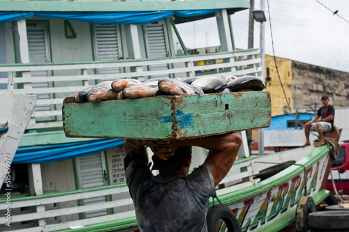 Strong man carrying a big box full of fish