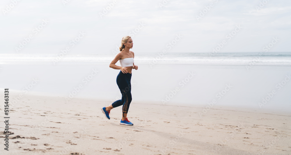 Full length view, Caucasian female with athletic sporty body running on seashore while training outdoors. Young woman working out and enjoying healthy lifestyle at nature. Runner moves on ocean beach Full length view, Caucasian female with athletic sporty body running on seashore while training outdoors. Young woman working out and enjoying healthy lifestyle at nature. Runner moves on ocean beach