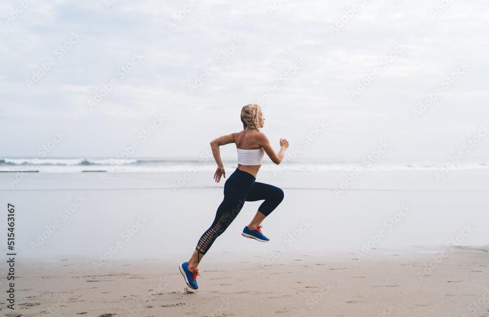 Full length view, Caucasian female with athletic sporty body running on seashore while training outdoors. Young woman working out and enjoying healthy lifestyle at nature. Runner moves on ocean beach Full length view, Caucasian female with athletic sporty body running on seashore while training outdoors. Young woman working out and enjoying healthy lifestyle at nature. Runner moves on ocean beach