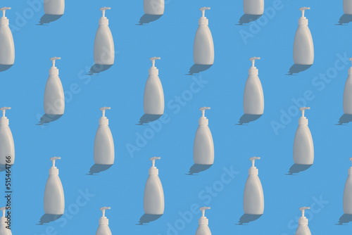Trendy pattern with antiseptic. White bottle of instant antiseptic hand sanitizer on blue background, no label.