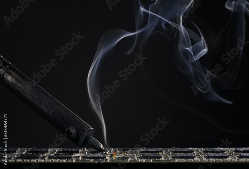 Billede på lærred Backdrop of smoking soldering iron on dark background.