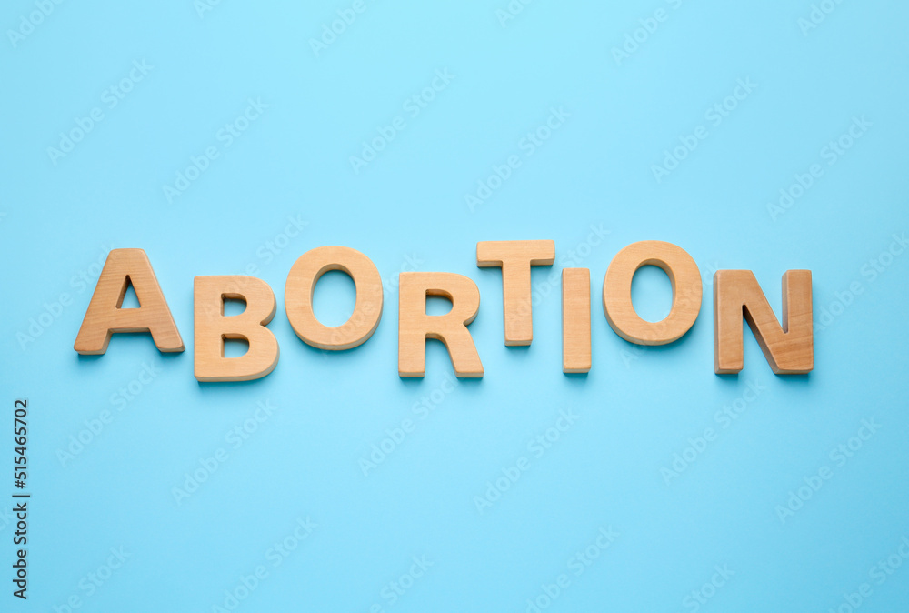 Word Abortion made of wooden letters on light blue background, flat lay Word Abortion made of wooden letters on light blue background, flat lay