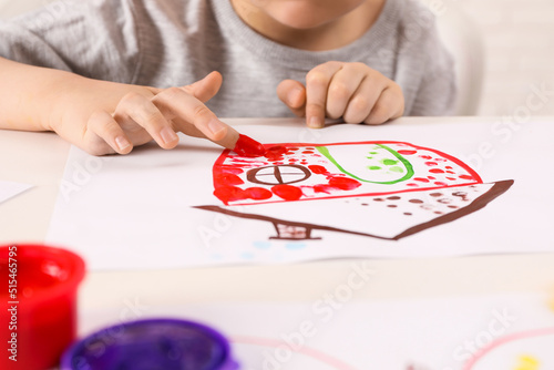Little boy painting with finger at white table indoors, closeup © New Africa