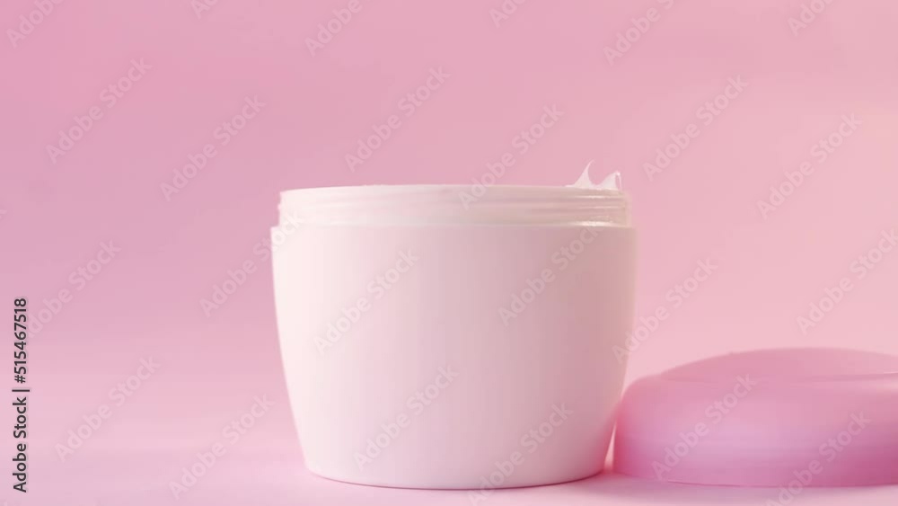 Hand taking skin from a skin cream bottle for women on pink background Hand taking skin from a skin cream bottle for women on pink background