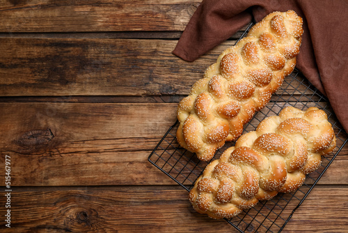 Homemade braided breads and cooling rack on wooden table, top view with space for text. Traditional Shabbat challah photo
