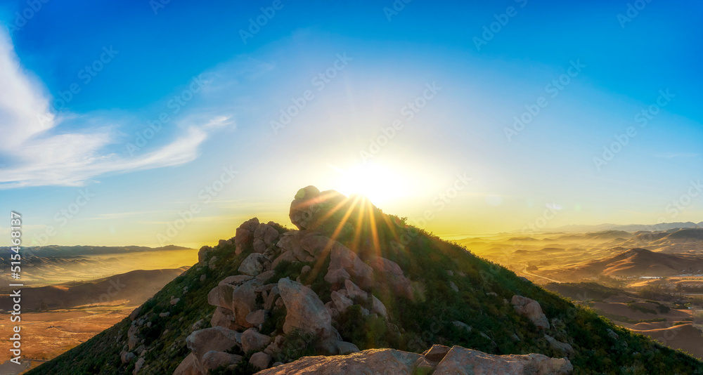 Panorama of mountain peak with sunburst, at sunset