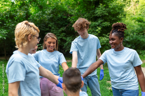 Group of multiracial volontaire young people building team outdoor in park, join hands together. photo