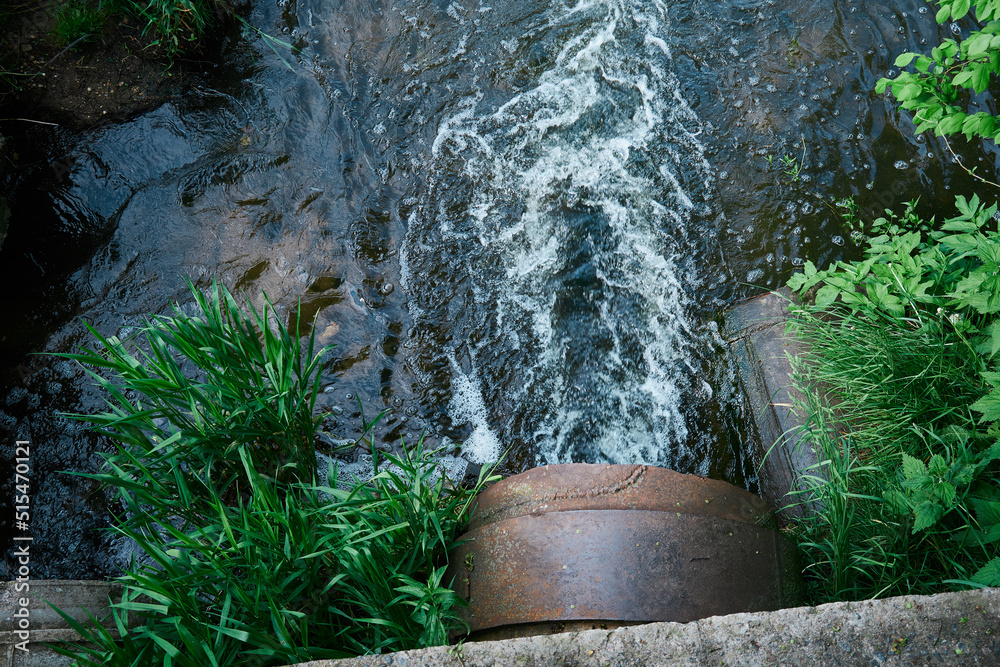 Concrete pipe transporting the polluted sewage water in to a small pond forest river waterfall