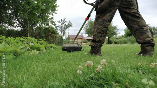 A gardener mows the grass in the garden with a brushcutter.
Ogrodnik kosi trawę w ogrodzie za pomocą wykaszarki. photo
