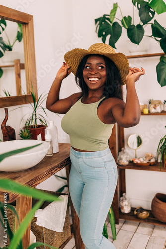 Portrait of young beauty woman indoors. Beautiful fashion woman at the bathroom dress up with straw hat for the sun.