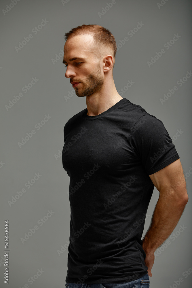 An attractive white man in jeans and black shirts tands in half growth against a gray background. Copy space An attractive white man in jeans and black shirts tands in half growth against a gray background. Copy space