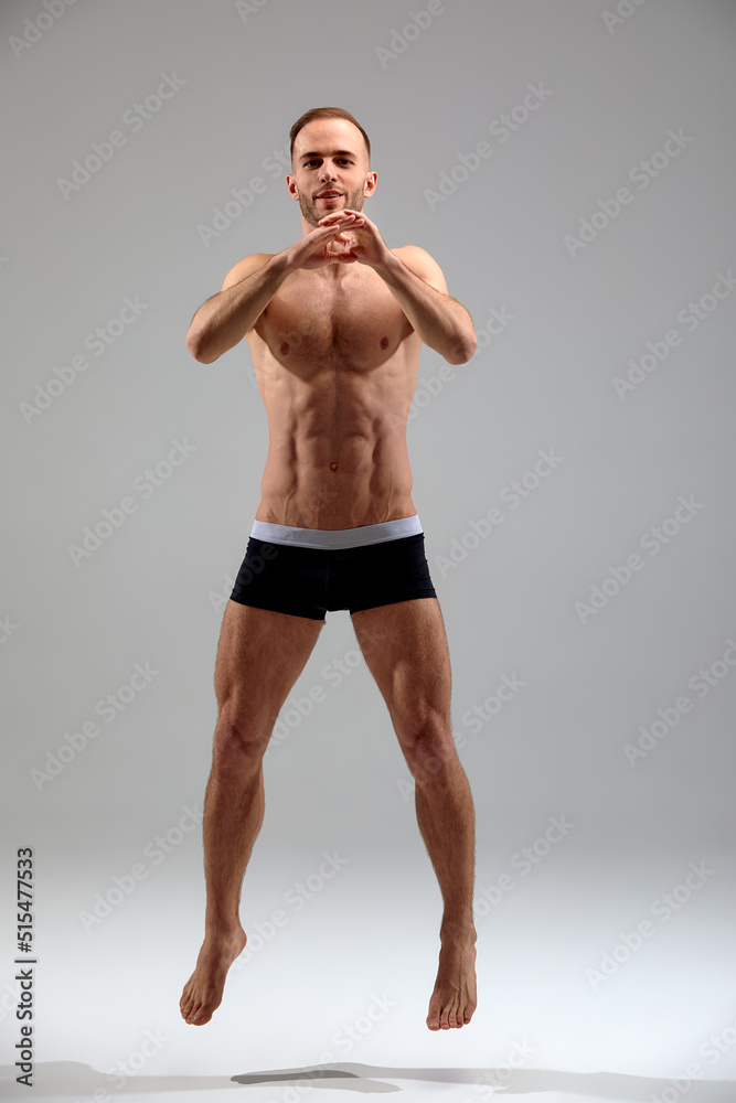 Full length portrait of a confident young sportsman shirtless jumping isolated over white background