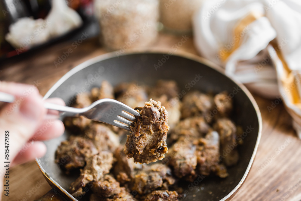homemade fried liver on a fork held in your hand in the kitchen (selective focus, blurred background) homemade fried liver on a fork held in your hand in the kitchen (selective focus, blurred background)