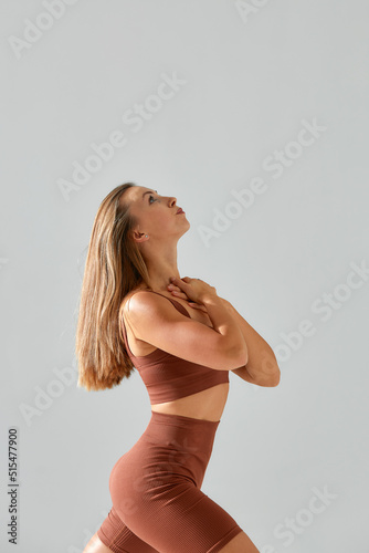 Young woman with beautiful slim healthy body posing in studio. Fitness female model in sportswear on grey background.