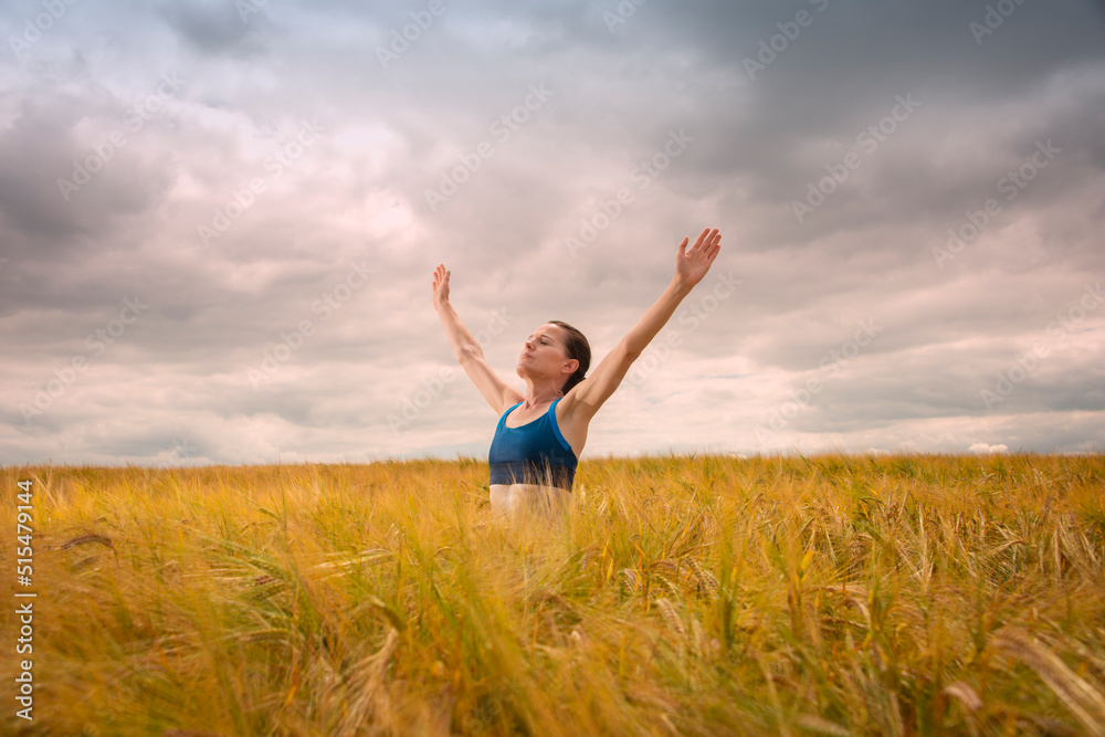 Woman with her arms raised in the middle of a field enjoying the summer and nature Woman with her arms raised in the middle of a field enjoying the summer and nature