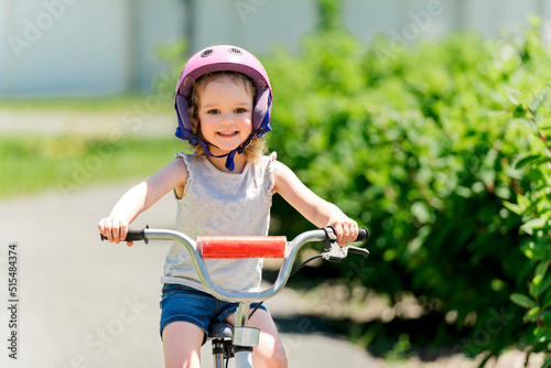 Fototapeta Naklejka Na Ścianę i Meble -  Children learning to drive a bicycle on a driveway outside. Little girls riding bikes on asphalt.