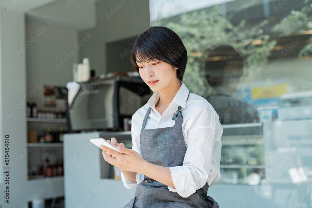 カフェ スマートフォンを使う女性スタッフ カフェ スマートフォンを使う女性スタッフ