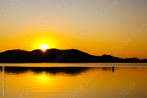 Sunrise behind mountains silhouettes with golden reflexion on water over a big lagoon