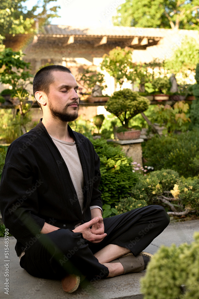 young handsome man meditating in the bonsai garden young handsome man meditating in the bonsai garden