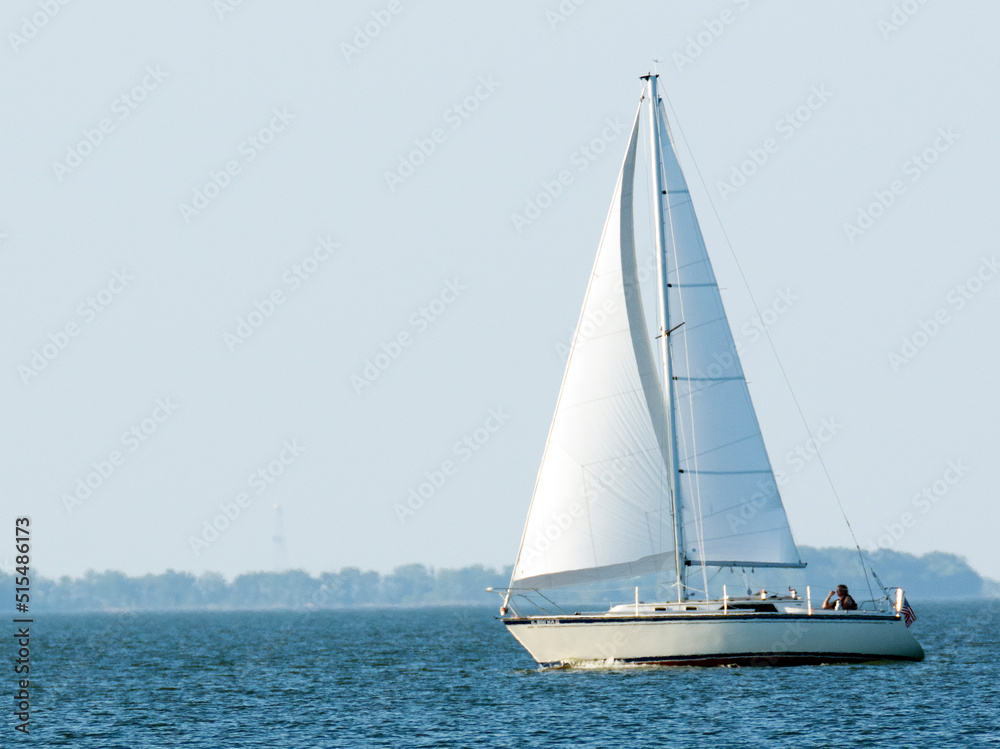 Fototapeta premium A white sailboat on blue water. 