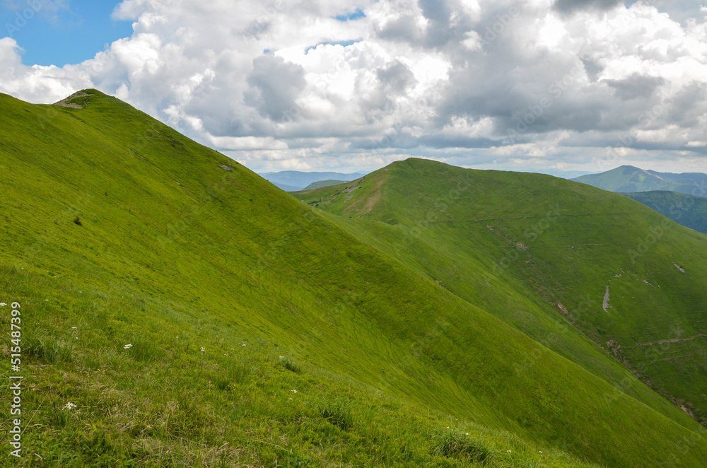 Green mountain ridge with steep slopes and high peak with a cross in the distance. Beautiful nature landscape of Carpathian Mountains, Ukraine