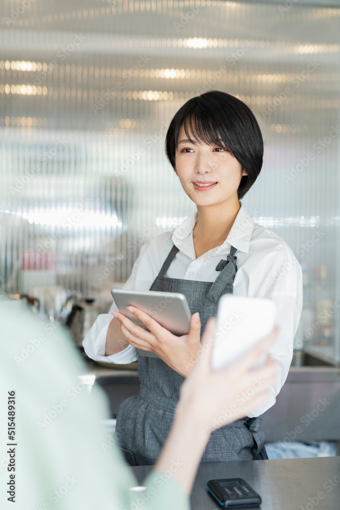 カフェ スタッフにスマートフォンを見せる女性 カフェ スタッフにスマートフォンを見せる女性