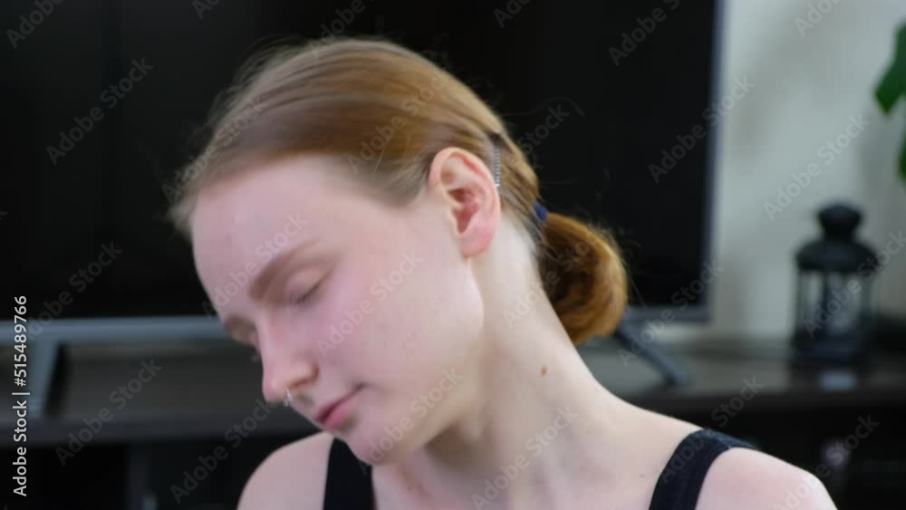 A young girl does an exercise on her neck. The girl goes in for sports in her apartment. Fitness at home. 4k A young girl does an exercise on her neck. The girl goes in for sports in her apartment. Fitness at home. 4k