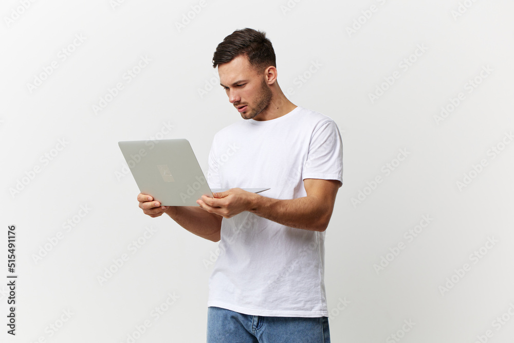 Unhappy angry tanned handsome man in basic t-shirt have problem with broken laptop posing isolated on over white studio background. Copy space Banner Mockup. Electronics repair IT concept Unhappy angry tanned handsome man in basic t-shirt have problem with broken laptop posing isolated on over white studio background. Copy space Banner Mockup. Electronics repair IT concept