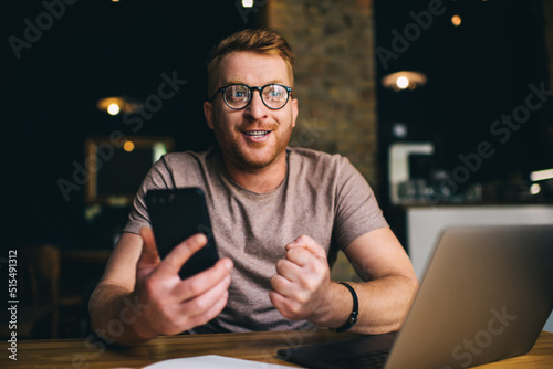 Canvas Print Young successful man celebrates good deal or a successful sports bet while using mobile phone