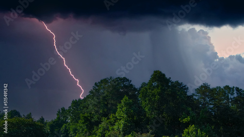 tall lush green trees with a gorgeous powerful storm clouds  and lightning at Dupree Park in Woodstock Georgia USA photo