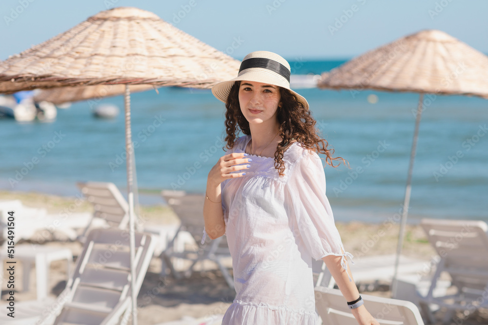 Happy teen girl having fun on the beach. Young brunette teenager girl with curly hair walking on the seashore in sunny day.