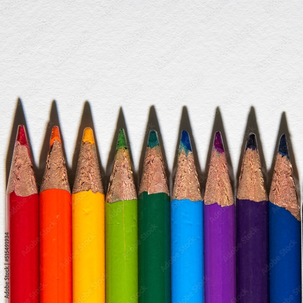 Aligned colored pencils and sharp tip shadows on white paper Aligned colored pencils and sharp tip shadows on white paper