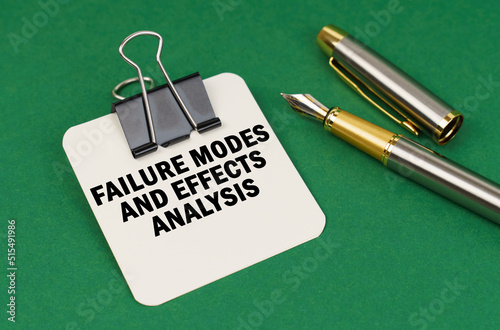 On a green surface, a pen and a sheet of paper with the inscription - Failure Modes and Effects Analysis photo